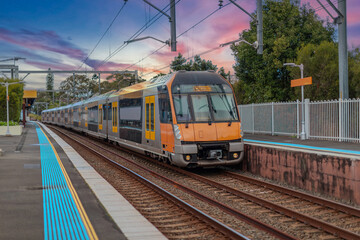 Obraz premium Passenger Train going through Lewisham Train Station at Sunset a suburban Sydney train Station in Sydney NSW Australia