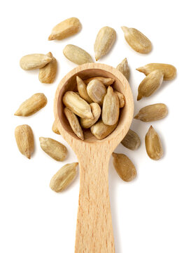 Sunflower seeds in a wooden spoon and scattered isolated on a white. Top view