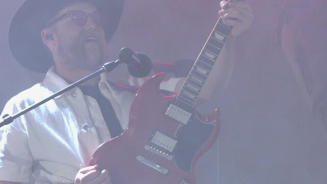 Male musician plays Gibson SG electric guitar enthusiastically on stage