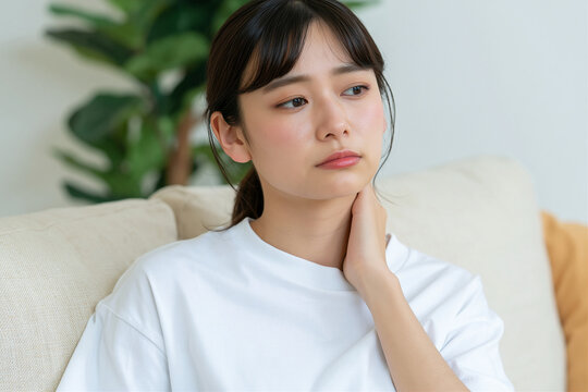 ソファで首の痛みに悩む若い女性