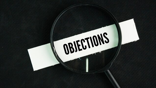 Magnifying glass with the word Objections. a reason or argument offered in disagreement, opposition, refusal, or disapproval
