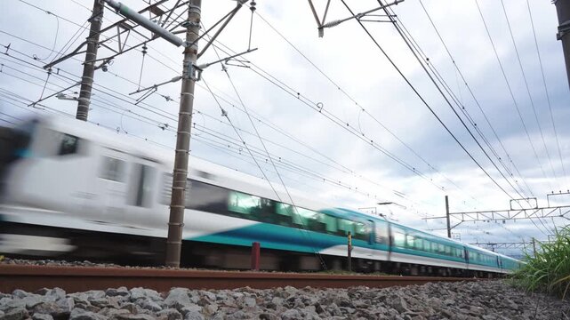 Dynamic low angle shot of a white and blue Japanese limited express train rushing past on a railway track
