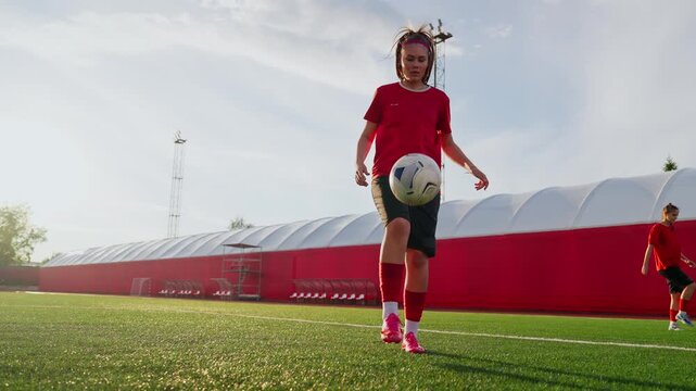 Focused womens soccer training sequence on modern turf field with athlete juggling ball in bright sunlight during individual footwork and ball control practice
