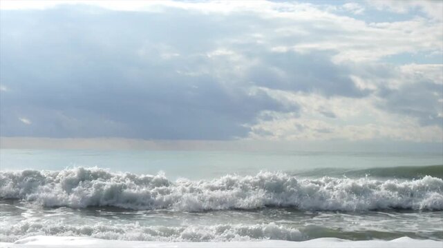 Powerful ocean waves crashing on sandy beach, dramatic cloudy sky, peaceful coastal seascape, natural sea surf, cinematic 4k nature background video