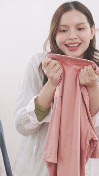 Close-up of a happy woman with closed eyes enjoying the fresh scent of laundered clothes.	