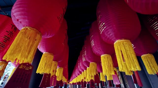 Low angle view of hanging red chinese lanterns swaying in row at traditional temple.