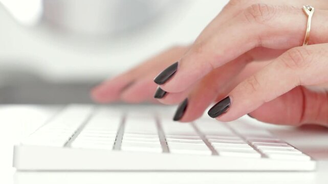 Close-up of woman applying false press-on nails. Manicured hands with adhesive nail art for salon or DIY beauty routine.