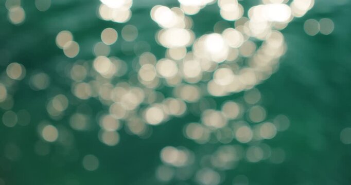 Sunlight reflects on turquoise sea water creating soft bokeh circles outdoors