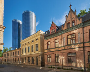 Naklejka premium Old brick houses on Balozu iela with futuristic glass skyscrapers in Pardaugava district of Riga.