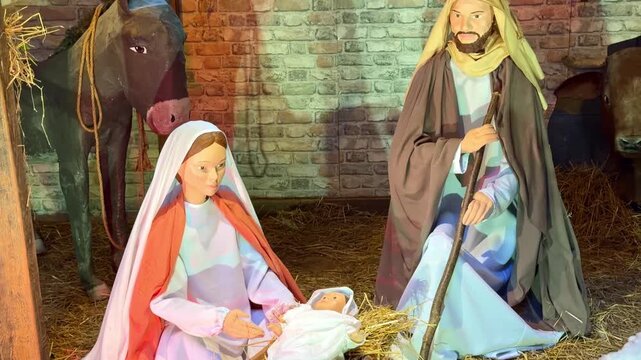 Christmas Nativity scene featuring Mary, Joseph and baby Jesus inside a traditional manger with straw, brick wall and ox, illustrating the Christian Christmas story, pan upward reveal.