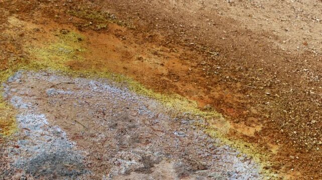 Static close up of colorful geothermal mineral deposits on hydrothermal ground in Lassen Volcanic National Park, California, showcasing sulfur stained earth and natural geothermal activity, USA