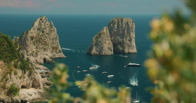 Boats and yachts cruising around Faraglioni sea rockss on a sunny summer day in Capri Italy