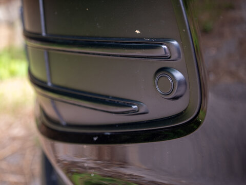 Close-up of a front parking sensor integrated into a modern car front bumper. Automotive safety technology designed to help drivers detect obstacles during parking maneuvers.