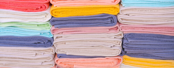 Folded Cotton Towels Stack in Pastel Colors Banner View © Екатерина Переславце