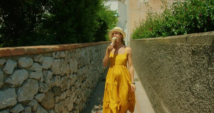 Tourist exploring streets of old town and enjoying ice cream in narrow sunlit alley in Capri Italy