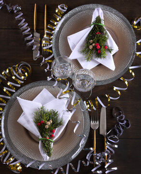 Festive New Year's table setting for two. Beautiful plates and garlands on the table. Concept of a Christmas or Thanksgiving family dinner. Top view
