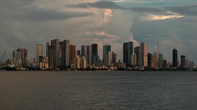 Cinematic day-to-night timelapse of the Mumbai skyline viewed across the Arabian Sea. Showcasing the city's iconic waterfront, urban growth, and vibrant metropolitan atmosphere in Maharashtra, India.
