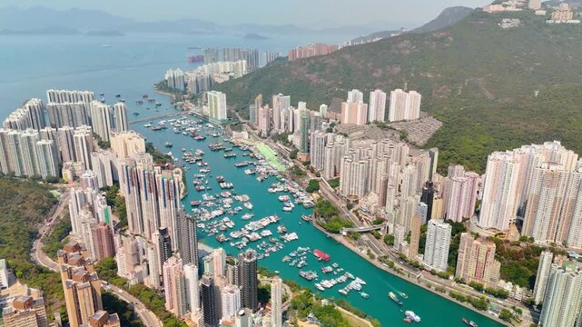 Harbor view with traditional fishing boats and modern yachts in front of tall residential skyscrapers in Hong Kong Kellet Bay