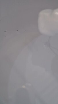 Footage of paint in a container being stirred slowly
