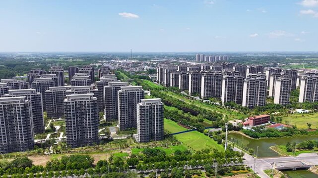 Aerial panoramic view of modern high-rise residential community with green landscape under blue sky