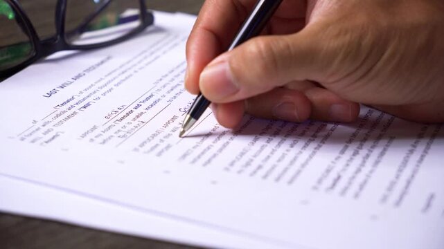 Person Writing on a Last Will and Testament Document
