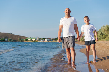 Fototapeta premium Man and a boy are walking on the beach