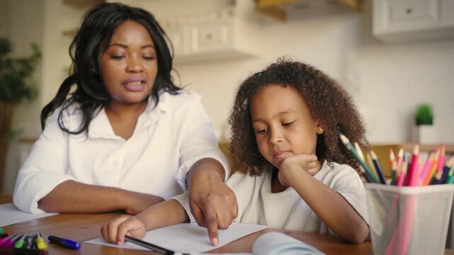 Portrait of cute six-years girl and mother or teacher at home, kids education. African american ethnicity, family time and home education, child studying english or foreign language, development