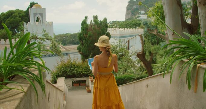 Young woman with map exploring summer garden terrace on Mediterranean coast