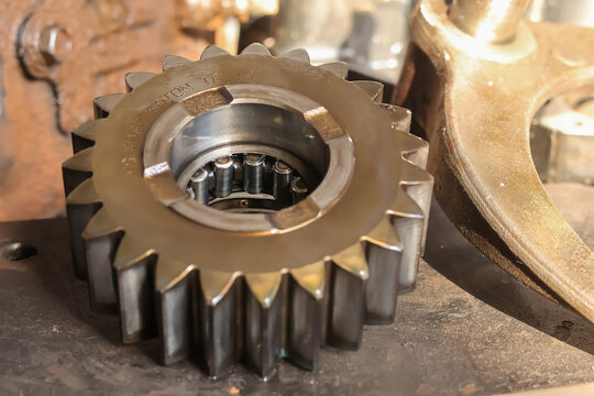 Detailed macro view of a heavy duty steel spur gear wheel and internal needle roller bearing mechanism inside a machine repair workshop.