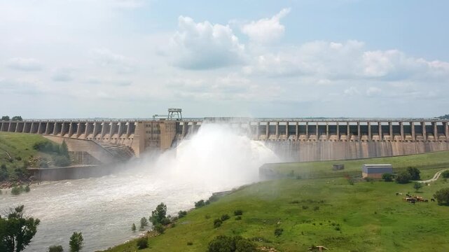 Aerial view of Vaal Dam wall releasing water through open sluice gates into river valley.