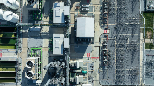 Aerial view combined cycle power plant with cooling tower and substation under blue sky, Industrial infrastructure of electric power station, exhaust stack and cooling systems.