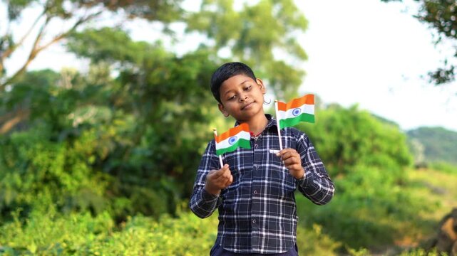 Patriotic Indian Child Holding Two Mini India Tricolour Flags in Indian Village. Rural Kid Celebrating Independence Day with Miniature Tiranga Flags.
