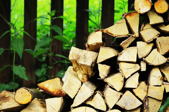 Stack of Cut Firewood Against Vibrant Green Backyard Scene for Rustic Outdoor Themes