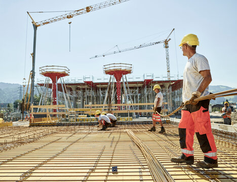 Workers on construction site preparing iron rods