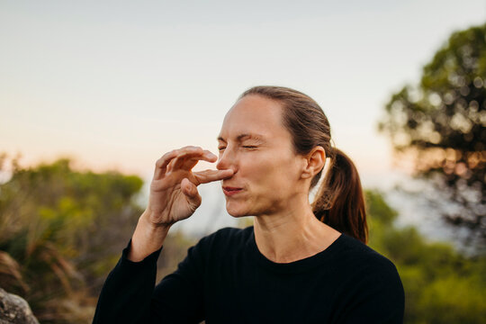 Woman with eyes closed scratching nose