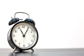 Naklejka premium Black Vintage Twin Bell Alarm Clock Showing Almost Twelve on White Background with Copy Space