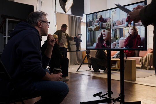 Director watches playback footage on a monitor at the indoor studio