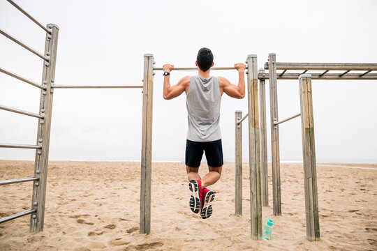 Young man doing chin-ups on the beach