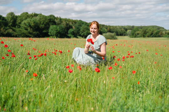 Carefree woman in dress enjoying nature in a summer poppy field