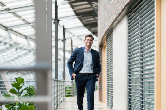 Confident businessman walking on gallery of green atrium