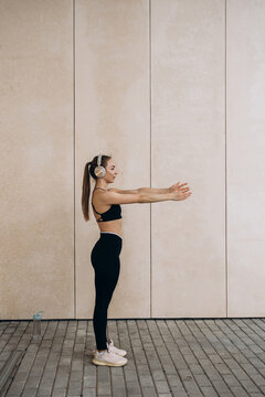 Woman stretches arms outdoors while listening to music