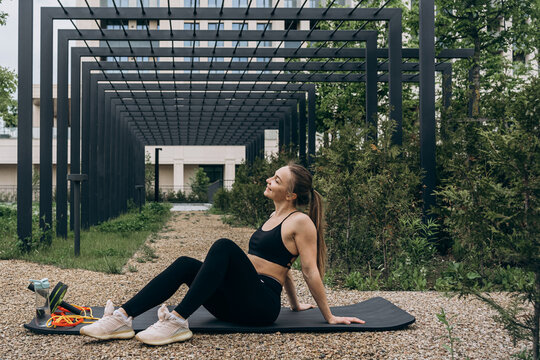 Smiling woman rests on mat during outdoor fitness training