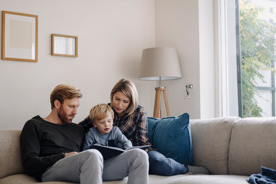 Family looking at book on couch at home