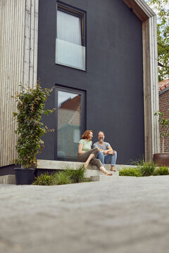 Cheerful couple sitting on steps outside tiny house