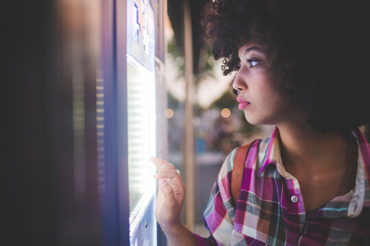 Young woman with afro hairdo using touchscreen vending machine in the city