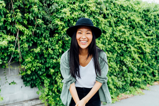 Happy beautiful woman wearing hat standing in front of plant
