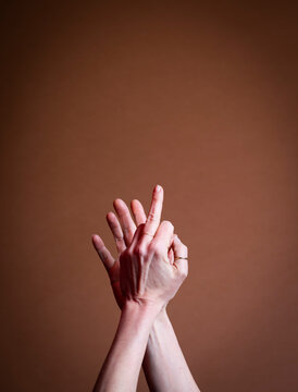 Close up of clasped hands gesturing against a brown background