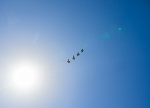 Four stealth fighters perform a formation flight in the blue sky