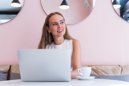 Thoughtful female freelancer with laptop sitting in cafe