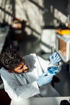 Scientist analyzing blue liquid in laboratory flask